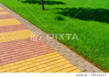 walkway made of paving slabs and green grass as a background, bright sunlight walkway made of paving slabs and green grass as a background, bright sunlight 76516137
