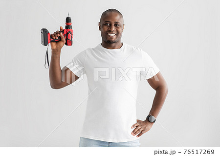 Instruments for renovation. Happy african american man holding electric drill, isolated on white background 76517269