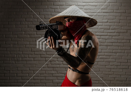 man in an Asian triangular hat with tattoos and a PPSh-41 airsoft gun and against the background of a brick wall man in an Asian triangular hat with tattoos and a PPSh-41 airsoft gun and against the background of a brick wall 76518618