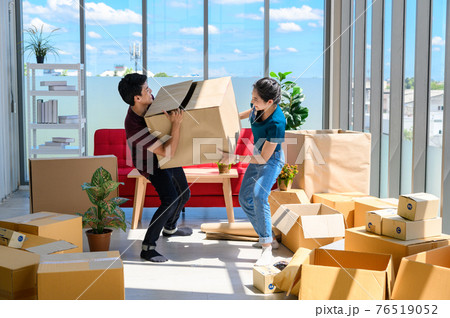 young asian couple smiling and enjoy when they carrying big cardboard box while relocation into new home on moving day, celebrating moving to new home concept 76519052