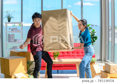 young asian couple smiling and enjoy when they carrying big cardboard box while relocation into new home on moving day, celebrating moving to new home concept young asian couple smiling and enjoy when they carrying big cardboard box while relocation into new home on moving day, celebrating moving to new home concept 76519058