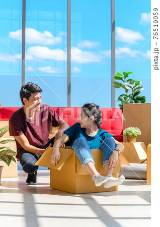 Happy young asian couple smiling relaxing and having fun while playing with cardboard box in new house, celebrating moving to new home concept 76519059