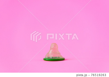 Green condom on pink paper background with copy space for text. Reproductive health and safe sex concept Green condom on pink paper background with copy space for text. Reproductive health and safe sex concept 76519263