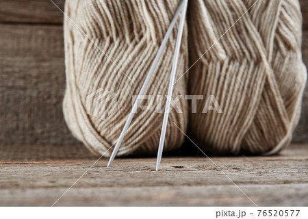 Two skeins of woolen yarn and needles for knitting on a wooden background Two skeins of woolen yarn and needles for knitting on a wooden background 76520577