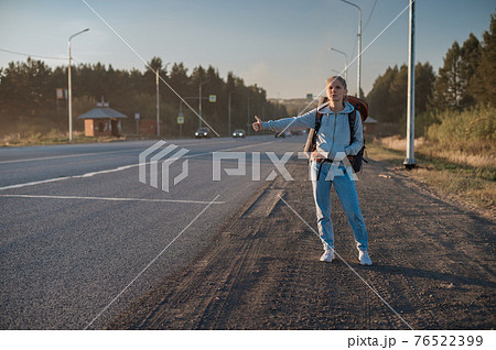 Travel woman with backpack hitchhiking on road 76522399