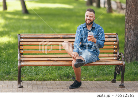 A guy with lemonade is resting in a park on a bench in the spring. Sunny day. A guy with lemonade is resting in a park on a bench in the spring. Sunny day. 76522565