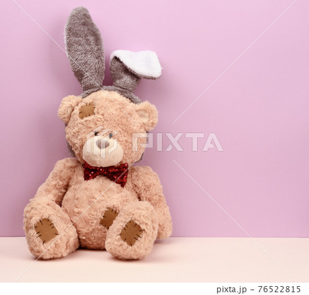 cute brown teddy bear wearing a rabbit mask with long ears on his head cute brown teddy bear wearing a rabbit mask with long ears on his head 76522815