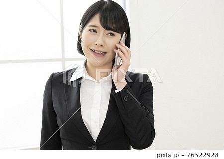 スーツ姿で電話をする若い女性 76522928