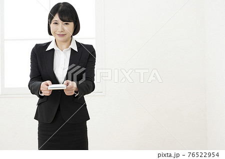 スーツ姿で名刺を差し出す若い女性（正面） 76522954