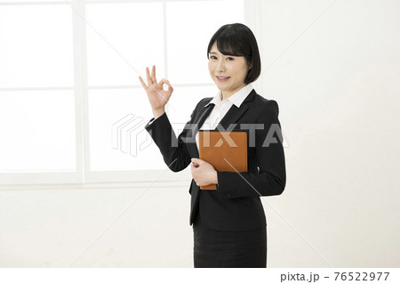 スーツ姿でシステム手帳を持ってポーズをとる女性 スーツ姿でシステム手帳を持ってポーズをとる女性 76522977