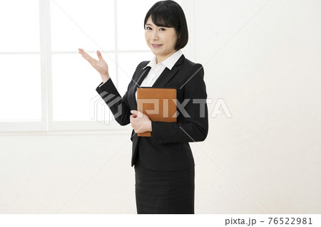 スーツ姿でシステム手帳を持ってポーズをとる女性 76522981