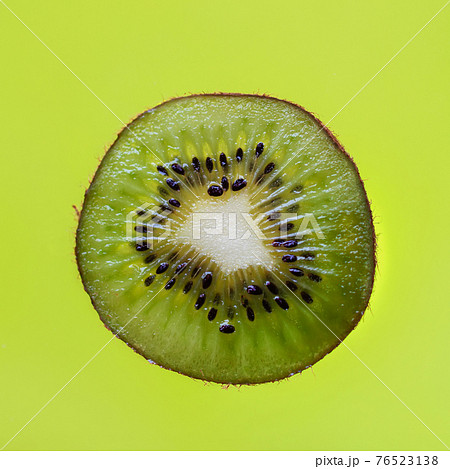 Freshly sliced kiwi fruit on green background close-up. Concept of diet and natural vitamins Freshly sliced kiwi fruit on green background close-up. Concept of diet and natural vitamins 76523138