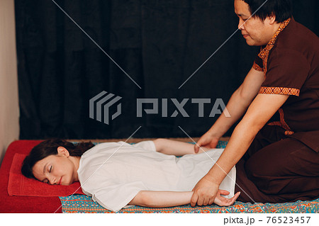 Thai man making classical thai massage procedure to young woman at beauty spa 76523457