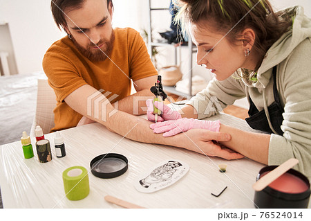 Woman making tattoo for her boyfriend at home during quarantine 76524014
