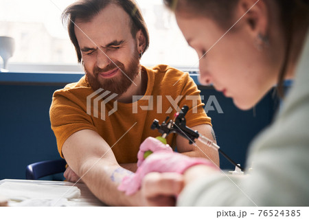 Woman making tattoo for her boyfriend at home with a rotary tattoo machine Woman making tattoo for her boyfriend at home with a rotary tattoo machine 76524385