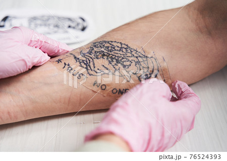 Woman in protective gloves transfer the sketch to the hand of her boyfriend 76524393