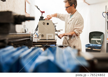 Man engineer wearing white robe working at the special machine while developing 76524802