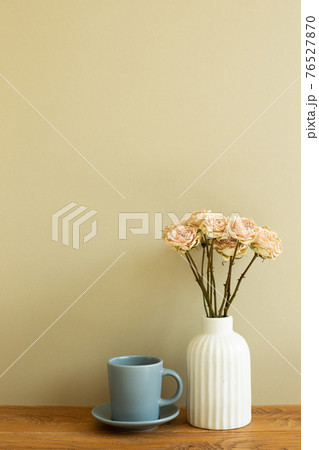 Coffee cup with dry rose flowers on wooden table. khaki beige background 76527870