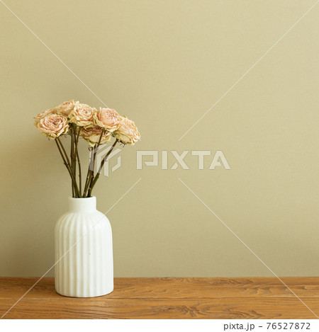 Vase of dry rose flowers on wooden table. khaki beige background 76527872