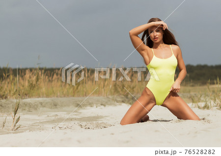 Alluring model in yellow swimsuit on sandy shore Alluring model in yellow swimsuit on sandy shore 76528282