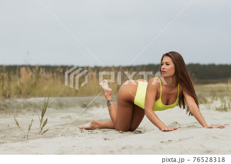 Erotic brunette in swimsuit posing on seashore 76528318