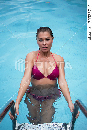 Slim woman standing on pool ladder 76528716