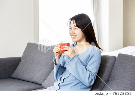 ソファーでくつろぐ若い女性 76528859