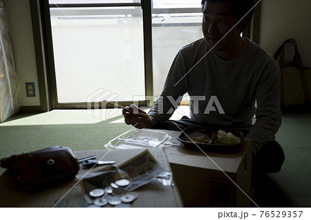 部屋で弁当を食べる男性 76529357