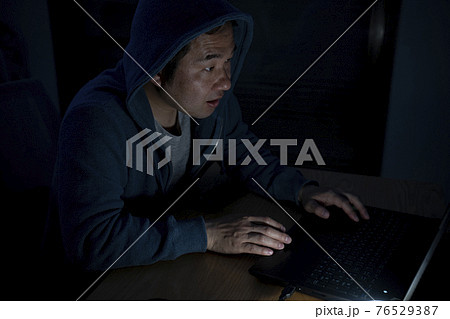 夜にパソコンを見る男性 76529387