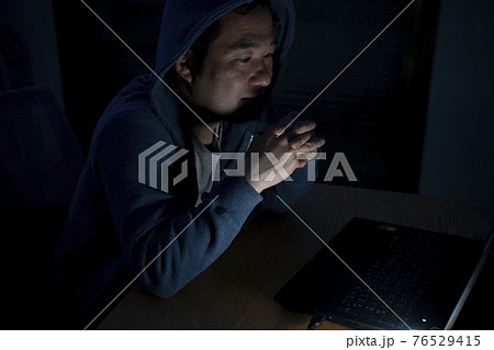 夜にパソコンを見る男性 76529415