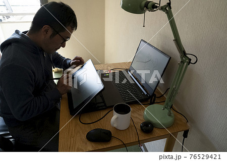ペンタブでイラストを描く男性 76529421