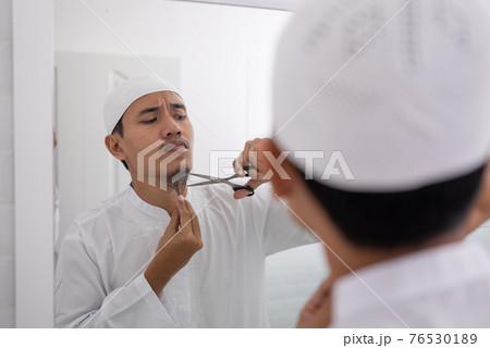 muslim asian man unsure to shave off his beard 76530189