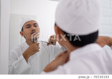 muslim asian man unsure to shave off his beard 76530193
