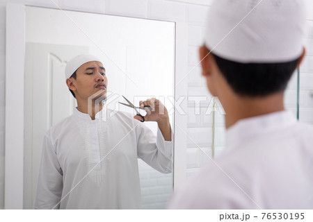 muslim asian man unsure to shave off his beard 76530195