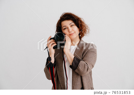 brunette woman in T-shirt and checkered jacket on a white background with camera 76531853
