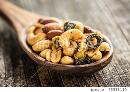 Mix of salted nuts in wooden spoon. 76533110