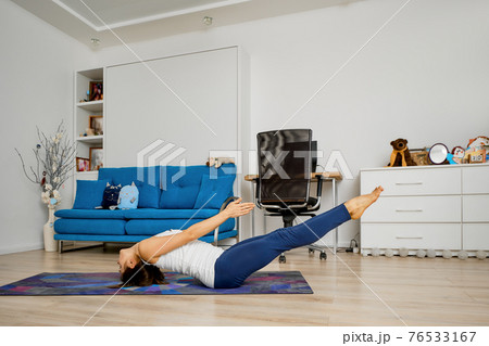 Woman does yoga at home in uttana padasana pose 76533167