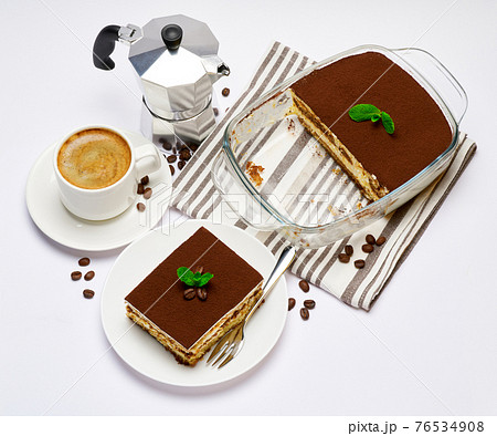 Traditional Italian Tiramisu dessert in glass baking dish, portion on plate and cup of coffee isolated on white background 76534908