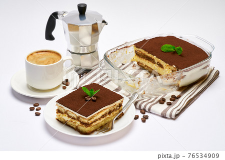Traditional Italian Tiramisu dessert in glass baking dish, portion on plate and cup of coffee isolated on white background 76534909