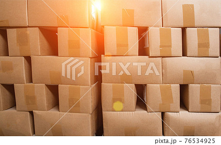 A pile of cardboard boxes on pallets against the backdrop of the sun. The concept of turnover, production, industry. Copy space 76534925
