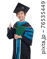 Asian boy student wearing graduation gown with ploma showing thumb on white background isolated 76535449