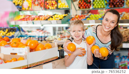 Portrait of happy woman and her little son choosing oranges at shop 76536252