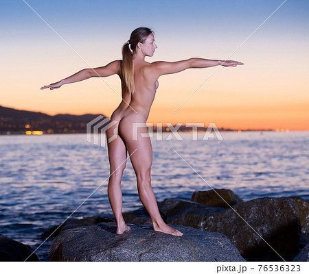 Nude girl is standing on a rock 76536323