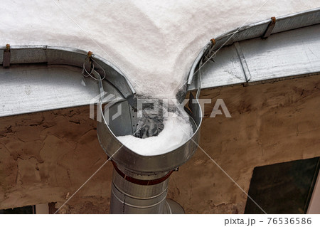 Frozen roof gutter clogged with snow and ice 76536586