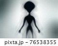Silhouette of spooky alien and bright light on behind him 76538355