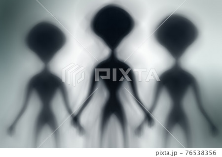 Silhouettes of spooky aliens and bright light on behind them 76538356
