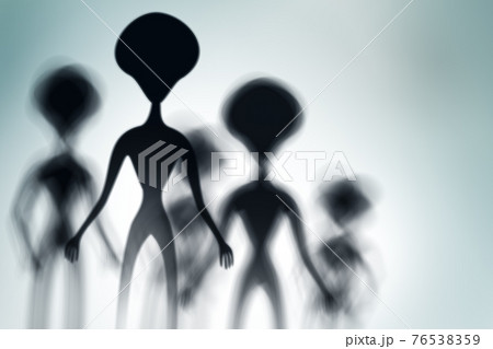 Silhouettes of spooky aliens and bright light on behind them 76538359