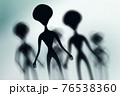 Silhouettes of spooky aliens and bright light on behind them 76538360