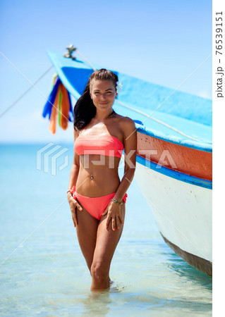 Sexy girl in red swimsuit posing at the tropical beach near to boat Sexy girl in red swimsuit posing at the tropical beach near to boat 76539151