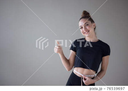 Beautiful fitness model with slim body measures the waist in a fitness club, Healthy nutrition and weight losing concept. 76539697